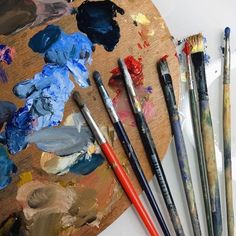 several paintbrushes are sitting on top of a wooden palette with different colors and shapes