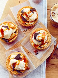 four desserts sitting on top of plastic wrappers next to a cup of coffee