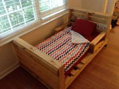 a wooden bed frame with red, white and blue sheets on it in a bedroom