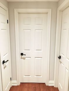 two white doors with black handles are open in a room that has wood floors and hard wood flooring