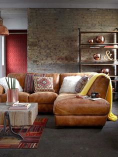 an image of a living room setting with brown leather couches and pillows on the floor