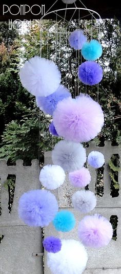 there are many purple and blue pom poms hanging from the ceiling