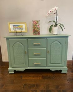 a green dresser with gold handles and drawers in a living room or dining room area