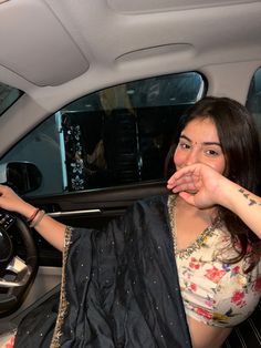 a woman sitting in the back seat of a car holding her hand up to her mouth