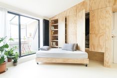 a bed sitting in the middle of a room next to a window and potted plant