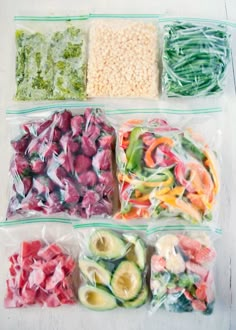 four plastic bags filled with different types of vegetables