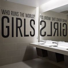 two sinks in a public restroom with mirrors above them that say girls who runs the world?