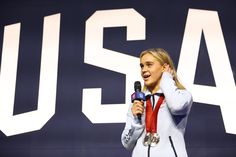 a female tennis player holding a microphone in front of a usa sign with the words usa on it