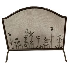 an iron fireplace screen with flowers painted on the front and back sides, set against a white background