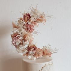 a white cake topped with flowers on top of a wooden table next to a wall