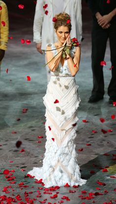 a woman in a white dress is holding a bow and rose petals on the ground