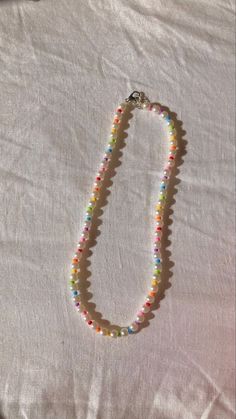 a multicolored beaded necklace laying on top of a white cloth covered bed