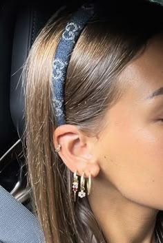 a woman with long hair wearing earrings and sitting in the back seat of a car