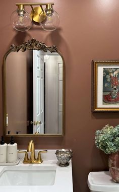 a bathroom with a sink, mirror and vase on the counter in front of it