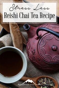 a red tea pot sitting on top of a table next to a cup of tea