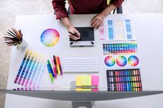 a person sitting at a desk with various color samples on it