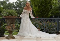 a woman in a white wedding dress standing on a balcony next to a planter