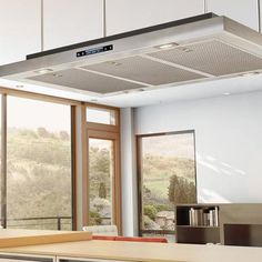 a kitchen with white cabinets and an overhead range hood over the stove top in front of sliding glass doors