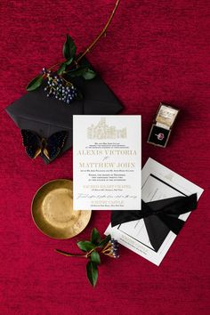 the wedding stationery is laid out on top of the red carpet, including an envelope and gold plate