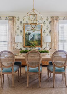 a dining room table with blue chairs and a painting on the wall