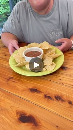 a man sitting at a table with a plate of chips and salsa