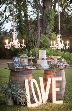 an outdoor table with wine barrels and candles on it that says love in the middle