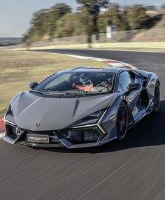 a silver sports car driving down a race track