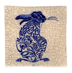 a blue and white tile with an image of a rabbit on it's back