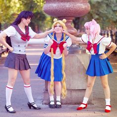 three girls dressed in sailor costumes standing next to a fountain