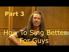 a man with long hair holding a guitar in front of a wooden wall and the words how to sing better for guys part one