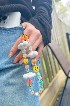 a woman's hand holding onto a bracelet with smiley face beads and buttons on it