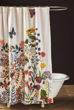 a shower curtain with colorful flowers and butterflies on it next to a white bathtub