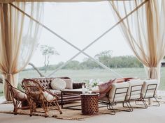 a living room filled with lots of furniture and windows covered in sheer draping