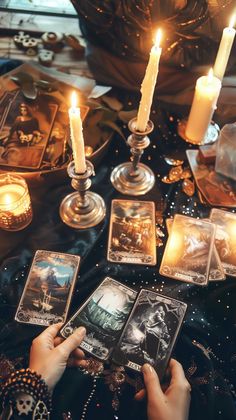 a person holding tarot cards in front of candles and other items on a table