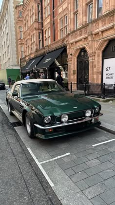 a green car is parked on the side of the street