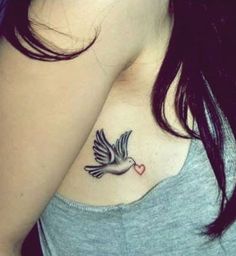 a woman's chest with a dove tattoo on the left side of her chest