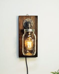 a mason jar light fixture mounted on a wall with a plugged in bulb attached to it