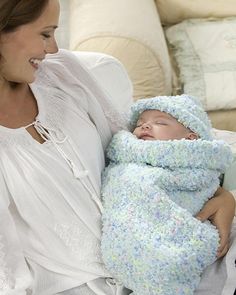 a woman holding a baby wrapped in a blanket