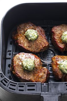 four steaks with green sauce on top in an air fryer