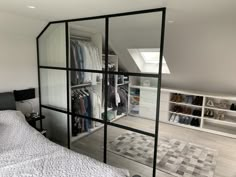 an attic bedroom with mirrored closet doors and clothes on the shelves in front of the bed