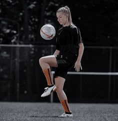 a young woman kicking a soccer ball on top of a field