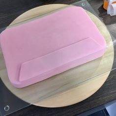 a pink cake sitting on top of a wooden plate