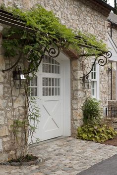 a stone house with vines growing on the front door and side windows, along with a brick walkway