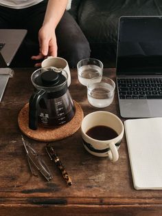 a person sitting at a table with two cups of coffee in front of their laptop