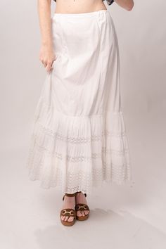 Enchanting Edwardian 1910’s white cotton petticoat maxi skirt with tiered tatted lace, a full skirt, and drawstring waist. Great vintage condition, with normal wear and condition for its age. Some faint spots and visible mending. Best fits modern size S/M Length 37”Waist up to 30” Featured top is the Gingham Graham Top from our friends at Psychic Outlaw. Model’s Measurements:Height 5’9”Chest 34”Waist 29”Hips 36.5” White Lace Vintage Bottoms, White Vintage Lace Bottoms, Vintage White Lace Bottoms, White Long Gathered Petticoat, White Long Petticoat With Gathered Skirt, Vintage White Long Skirt, Long Cotton Skirt With Lace Trim, Cotton Long Skirt With Lace Trim, White Bohemian Maxi Skirt For Daywear