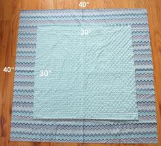 the measurements for a quilted placemat on a wooden floor with blue and white chevron