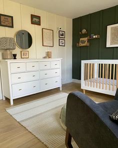 a baby's room with green walls, white furniture and pictures on the wall