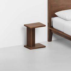 a bed with a wooden headboard and foot board next to a night stand on the floor