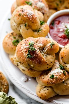 small rolls on a white plate with dipping sauce in the middle and other appetizers around them