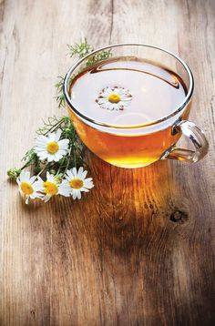 a cup of tea with some daisies in it